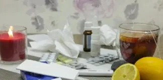 Čaj, citrón, sviečka a lieky na stole počas prechladnutia